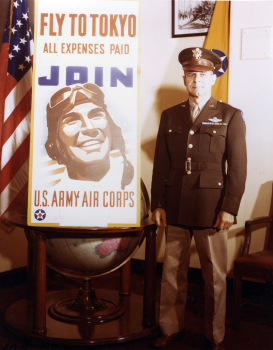 Brig. Gen. James Doolittle poses beside an Air Corps recruiting poster that alludes to his bombing raid on Japan in April 1942. (c) 1943