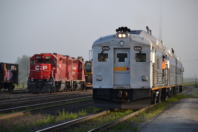 Eastbound train 186, with the RDC baggage car in the lead, passes a CP freight train carrying backhoes at the small White River, ON yard on June 19, approaching the station to begin its run towards Sudbury. (Photo by Malcolm Kenton)